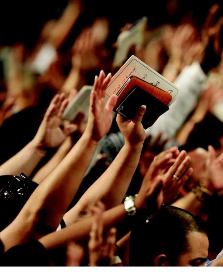Raising hands in worship with Bibles in Shine India Ministries